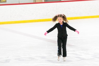 Küçük kız buz pistinde artistik patinaj yapıyor..