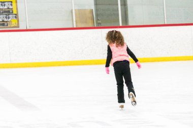 Küçük kız buz pistinde artistik patinaj yapıyor..