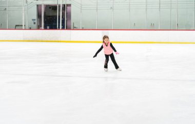 Küçük kız buz pateni pistinde artistik patinaj yapıyor..