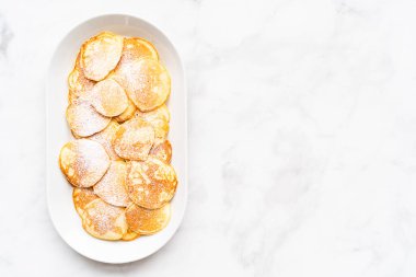 Düz yatıyordu. Süslü şekerle süslenmiş kefir tabanında taze yapılmış küçük krepler..