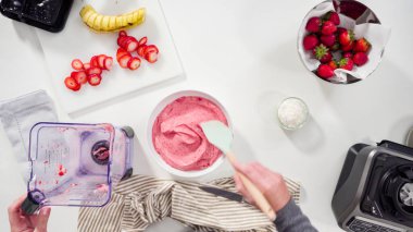 Düz yatıyordu. Mutfak blendırında çilekli ve muzlu smoothie hazırlıyorum..