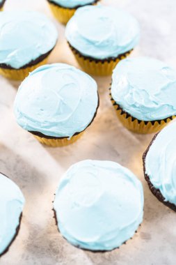 Çikolatalı kekleri tereyağlı krema ve gökkuşağı şekeriyle süslüyorum..