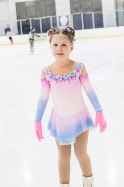 Küçük kız buz pateni pistinde artistik patinaj yapıyor..