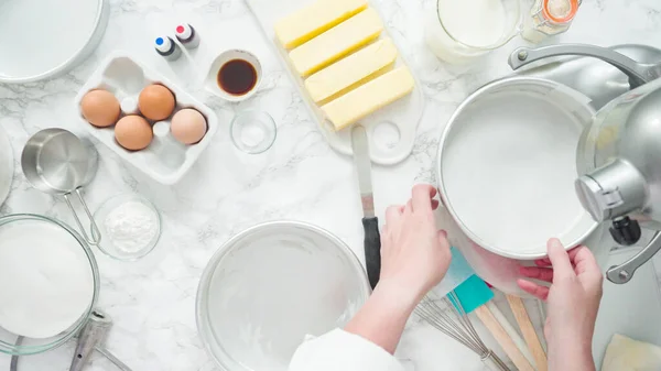 Step by step. Flat lay. Greasing cake pans with butter to bake a three-layer vanilla cake.