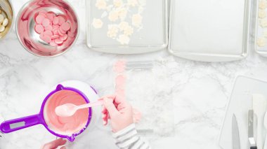 Düz yatıyordu. Adım adım. Erimiş çikolatayı kar taneleri şeklinde plastik bir çikolata kalıbına döküyorum..