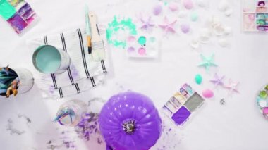 Little girl painting small craft pumpkin with acrylic paint.