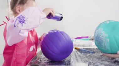 Little girl painting small craft pumpkin with acrylic paint.