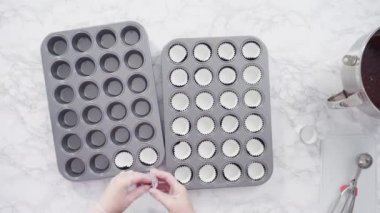 Çikolatalı ahududu kekleri pişirmek için folyolu kek bardaklarıyla kaplı kek tepsisi..