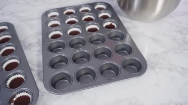 Çikolatalı ahududu kekleri pişirmek için folyolu kek bardaklarıyla kaplı kek tepsisi..