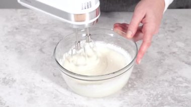 Kadın cam kavanoza un döküyor. Beyaz arka planda çırpılmış çırpıyla. 