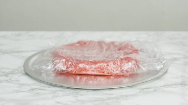 Adım adım. Taze pişmiş kek katmanlarını temiz gıdaya sarıyorlar.