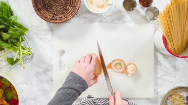 Düz yatıyordu. Adım adım. Tek demlik makarna tarifi yapmak için beyaz bir kesim tahtasıyla sebze kesmek..