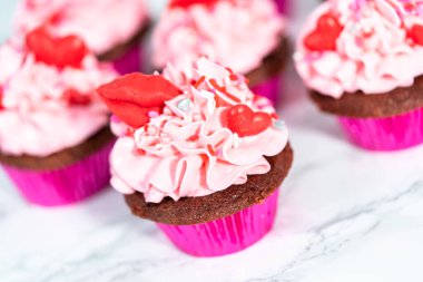 Pembe İtalyan kremalı kırmızı kadife kekler ve kalp ve öpücük şeklinde kırmızı çikolatalarla süslemeler..