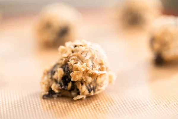 Scoops of cookie dough on a baking cheets to bake chewy oatmeal raisin cookies.