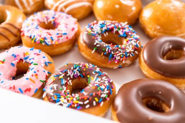 Beyaz bir karton kutuda mağazadan alınmış donutların çeşitliliği.