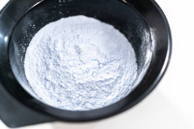 Siyah plastik bir kasede beyaz arka planda saç boyası tozu..