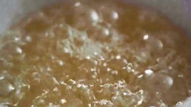 Manzarayı kapat. Ev yapımı lolipop yapmak için tencerede karamelize şeker.