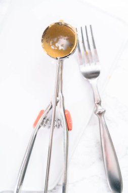 Kirli hamur kepçesi ve beyaz bir seramik tahtada çatal..