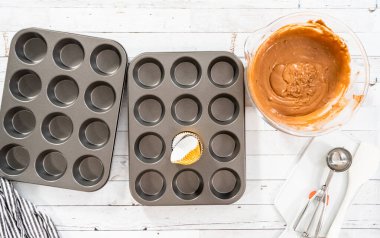 Düz yatıyordu. Çikolatalı ahududu kekleri pişirmek için folyolu kek bardaklarıyla kaplı kek tepsisi..