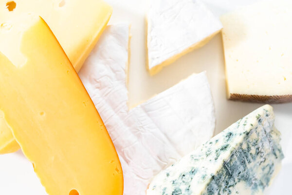 Variety of large wedges gourmet cheese on a white background.