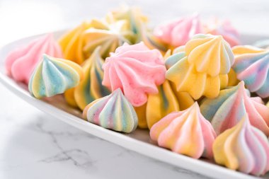 Beyaz servis tabağında çok renkli tek boynuzlu at kurabiyeleri..