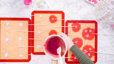 Düz yatıyordu. Ev yapımı lolipoplar yapmak için silikon paspaslara karamelize şeker dökmek..