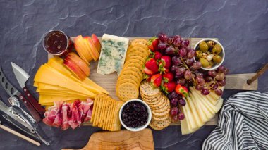 Düz yatıyordu. Büyük bir peynir tahtası için tahtanın üzerinde gurme peynir, kraker ve meyve düzenlemek.