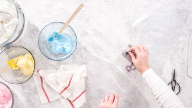 Düz yatıyordu. Adım adım. Tek boynuzlu at meringue kurabiyesi pişirmek için metal uçlu boru torbalarına krema karıştırılıyor..