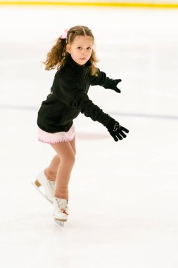 Küçük kız buz pateni pistinde artistik patinaj yapıyor..