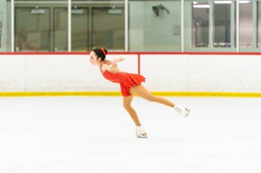 Genç kız buz pateni pistinde artistik patinaj yapıyor..