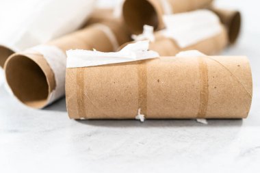 Gri arkaplanda boş tuvalet kağıdı ruloları kullanılıyor.