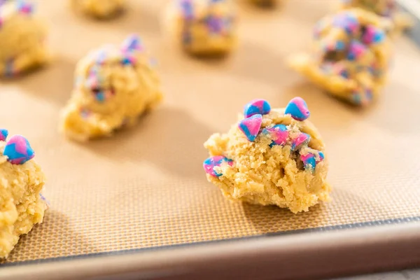 Chilled cookie dough scoops on the baking sheet to bake unicorn chocolate chip cookies.