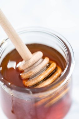 Küçük cam bir kavanozda organik bal ve ahşap bal kaplama..