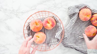 Düz yatıyordu. Adım adım. Mermer arka planda sepetteki organik şeftaliler..