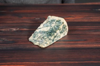 Koyu ahşap arka planda büyük bir dilim mavi peynir..