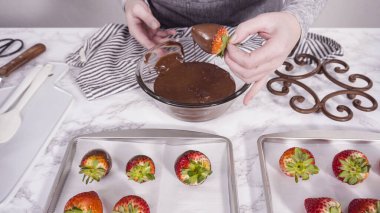 Adım adım. Çikolata kaplı çilek hazırlamak için organik çilekleri erimiş çikolatayla bir kaseye daldırmak..