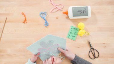 Küçük kız annesiyle el sanatları masasında dikiş dikmeyi öğreniyor..