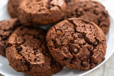 Taze pişmiş çifte çikolatalı kurabiyeler beyaz tabakta..