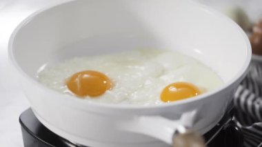 Manzarayı kapat. Beyaz tavada taze yumurta kızartıyorlar..