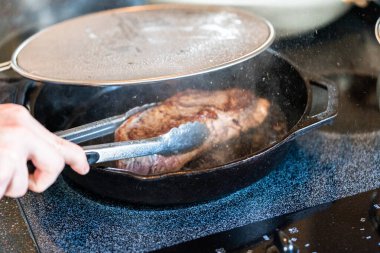 Elektrikli fırının üstünde kızgın demir tavayla New York bifteği kızartıyorum..