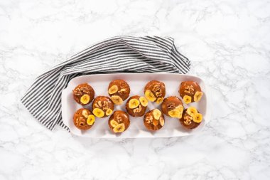 Düz yatıyordu. Ceviz ve muz cipsiyle süslenmiş, ev yapımı karamel serpiştirilmiş muzlu fındıklı çörekler pişirir..