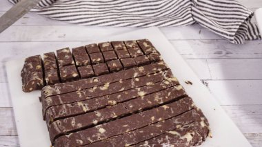 Adım adım. Beyaz kesim tahtasında ev yapımı macadamia şekerlemesi kesiyorum..