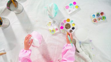 Düz yatıyordu. Evde resim dersinde kağıt heykel boyayan küçük bir kız..