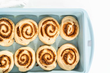 Fırınlanmamış tarçınlı çörekler mavi bir tavada.