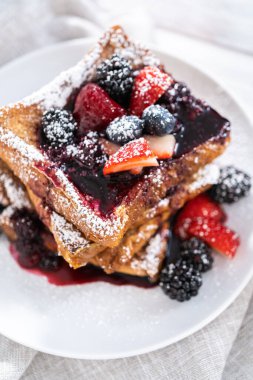 Karışık böğürtlen ezmesi ve pudra şekeriyle süslenmiş taze yapılmış tost..