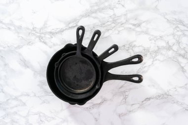 Düz yatıyordu. Mermer arka plan üzerinde dökme demir kızartma tavaları.