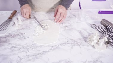 Adım adım. Mermer tezgahın üzerindeki beyaz fondanla kar tanelerini keserek..