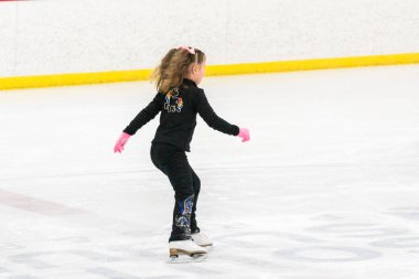 Küçük kız buz pistinde artistik patinaj yapıyor..