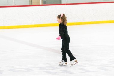 Küçük kız buz pistinde artistik patinaj yapıyor..