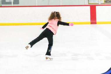 Küçük kız buz pistinde artistik patinaj yapıyor..